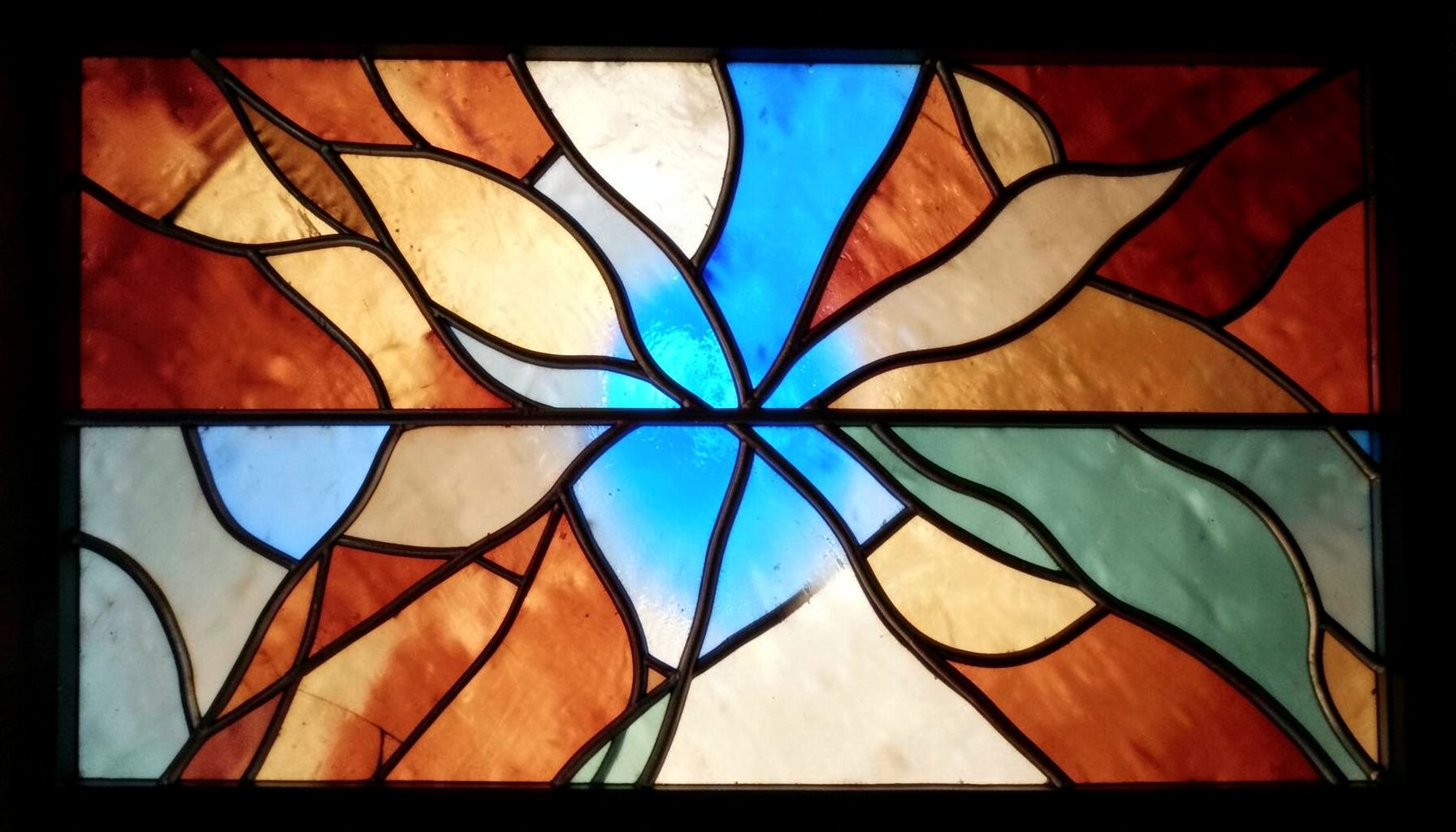 A stained-glass arrangement in warm terracotta, cream, and sage with organic flowing lead lines suggesting natural botanicals.