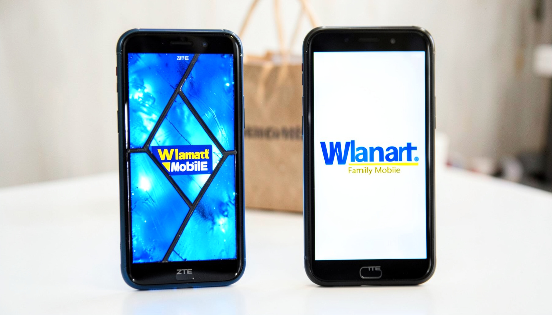 Two ZTE smartphones side by side on a bright white surface, one displaying the Walmart Family Mobile logo in blue and yellow, with a shopping bag softly blurred behind.