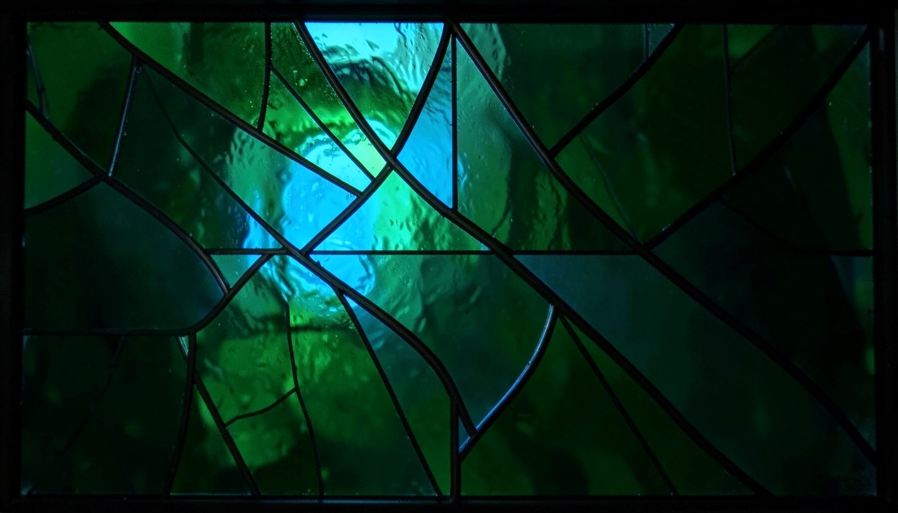 A stained-glass design in deep forest green and charcoal with crisp geometric lead lines, conveying a sleek, modern feel.